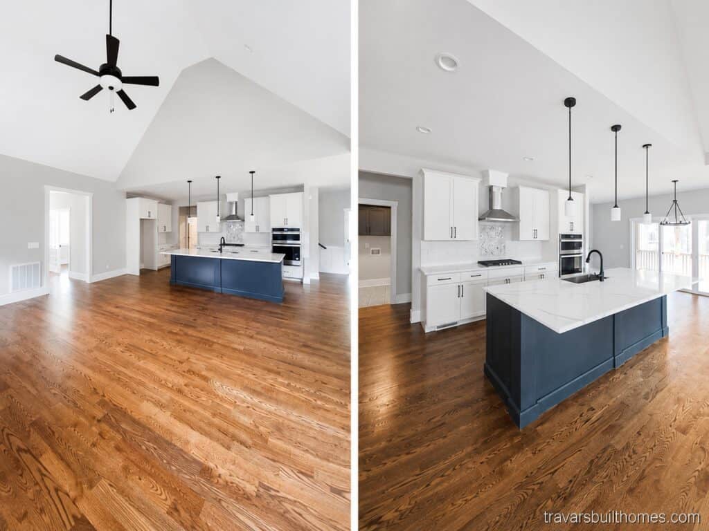 Split view of a bright open-concept kitchen highlighting a striking dark blue center island, crisp white perimeter cabinetry, stainless steel double ovens, and a soaring vaulted ceiling, crafted by Travars Built Homes.