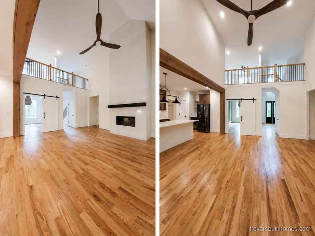 Split view of a grand two-story living room detailing a towering white tile fireplace and an overlooking loft on the left, with a seamless flow under a rustic wood beam into the kitchen on the right, by Travars Built Homes.