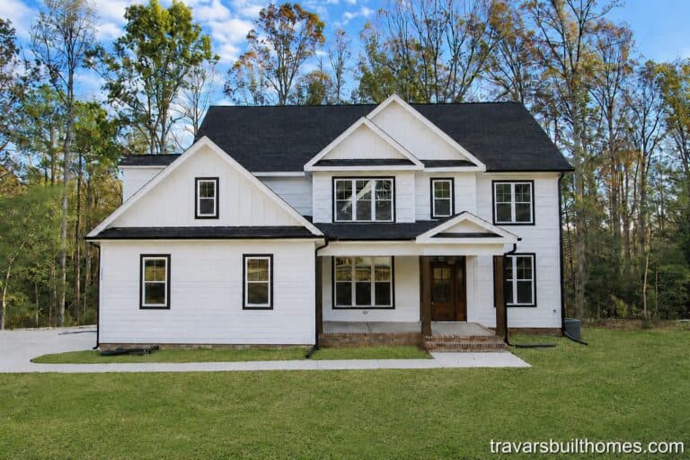 Beautiful custom modern farmhouse exterior showcasing crisp white siding, striking black window frames and roofing, natural wood porch columns, and an elegant wood front door, built by Travars Built Homes.